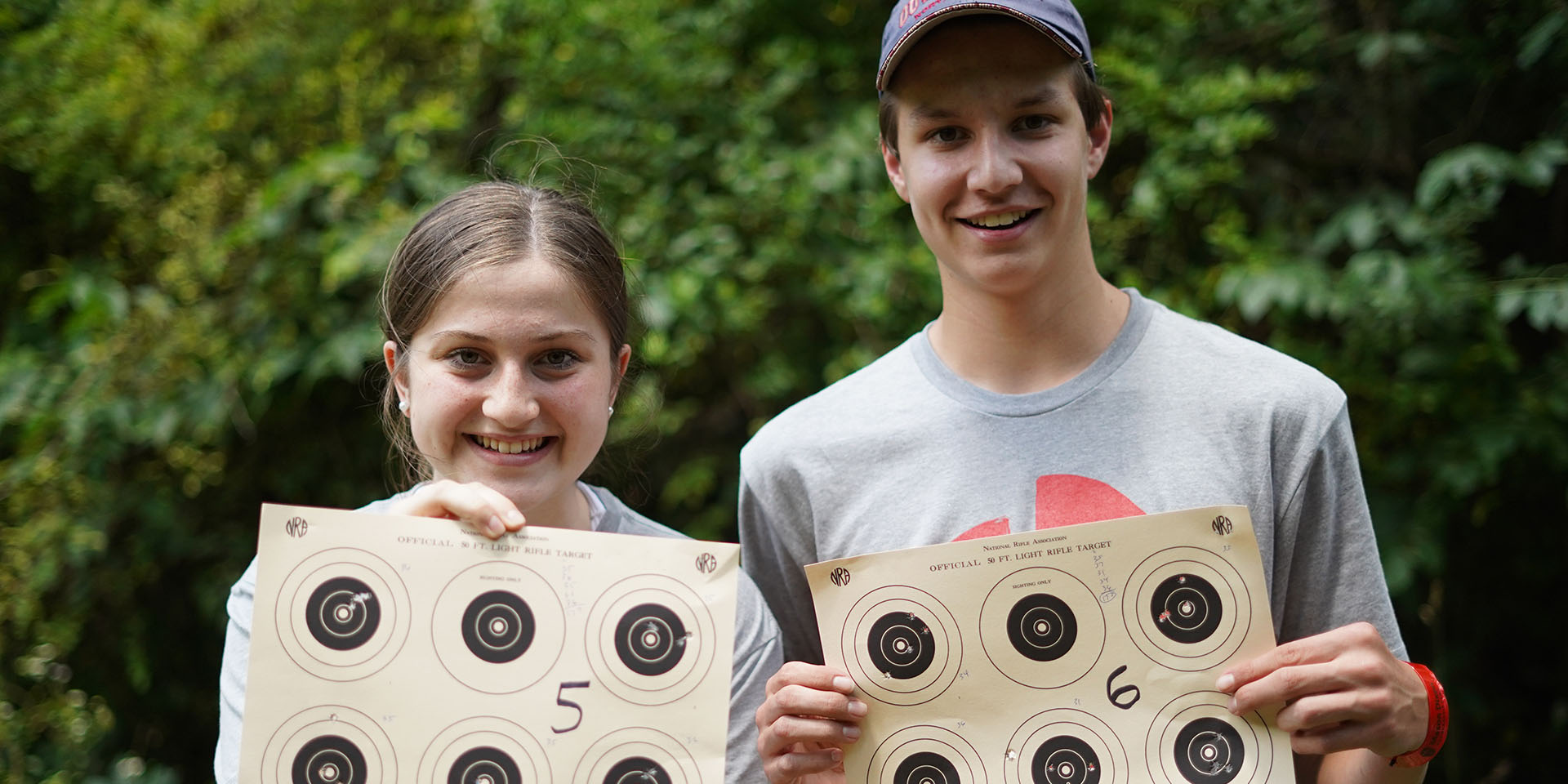 Two campers hold up their rifle range targets.